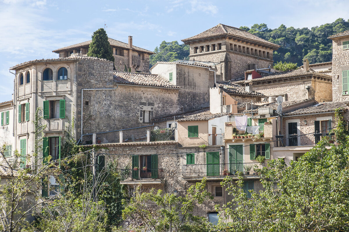 Natursteinhäuser von Valldemossa mit grünen Fensterläden vor bewaldeten Bergen